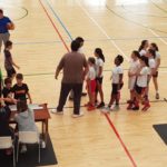 Árbitro, entrenadores y jugadores, chicos y chicas, al final del partido amistoso